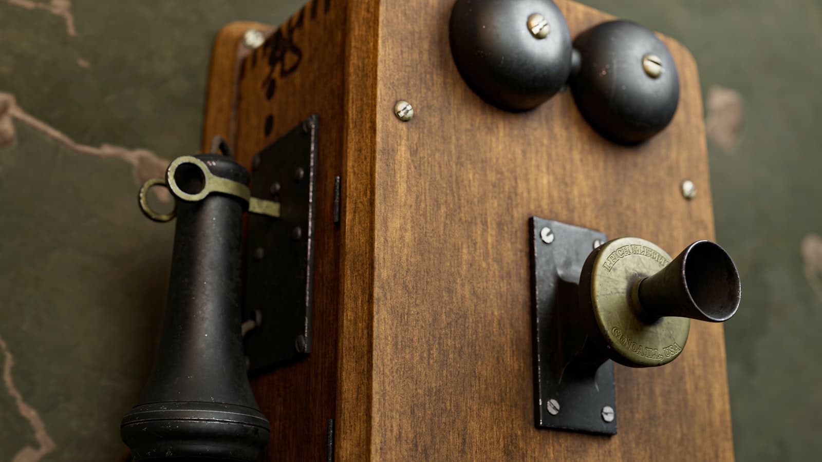 Editorial photograph of a vintage 1950s telephone switchboard with brass plugs and braided cables, lit by a dramatic spotlight from above.